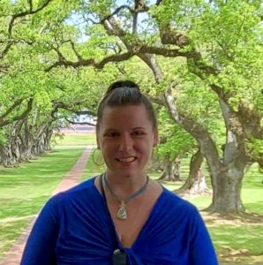 Headshot of author Lydia Stevens wearing a bright blue shirt outdoors on a sunny day