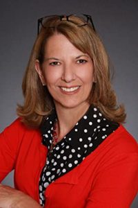 Headshot of author Barabara Wallace wearing a red sweater and a navy-and-white scarf around her neck